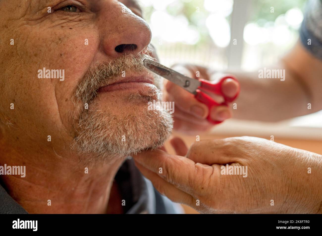 Hände einer älteren Frau, die den Schnurrbart des Mannes schneidet Stockfoto