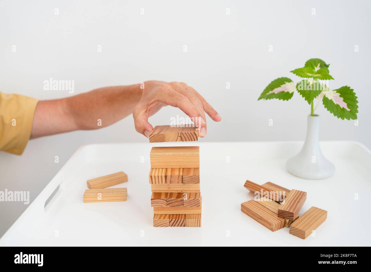 Hand eines Mannes, der Holzblöcke auf den Couchtisch stapelte Stockfoto