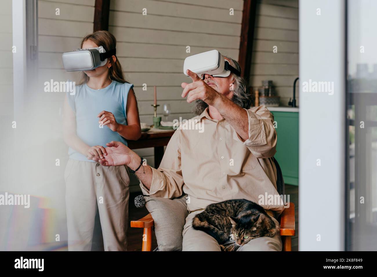Enkelin und Großvater tragen zu Hause eine VR-Brille Stockfoto