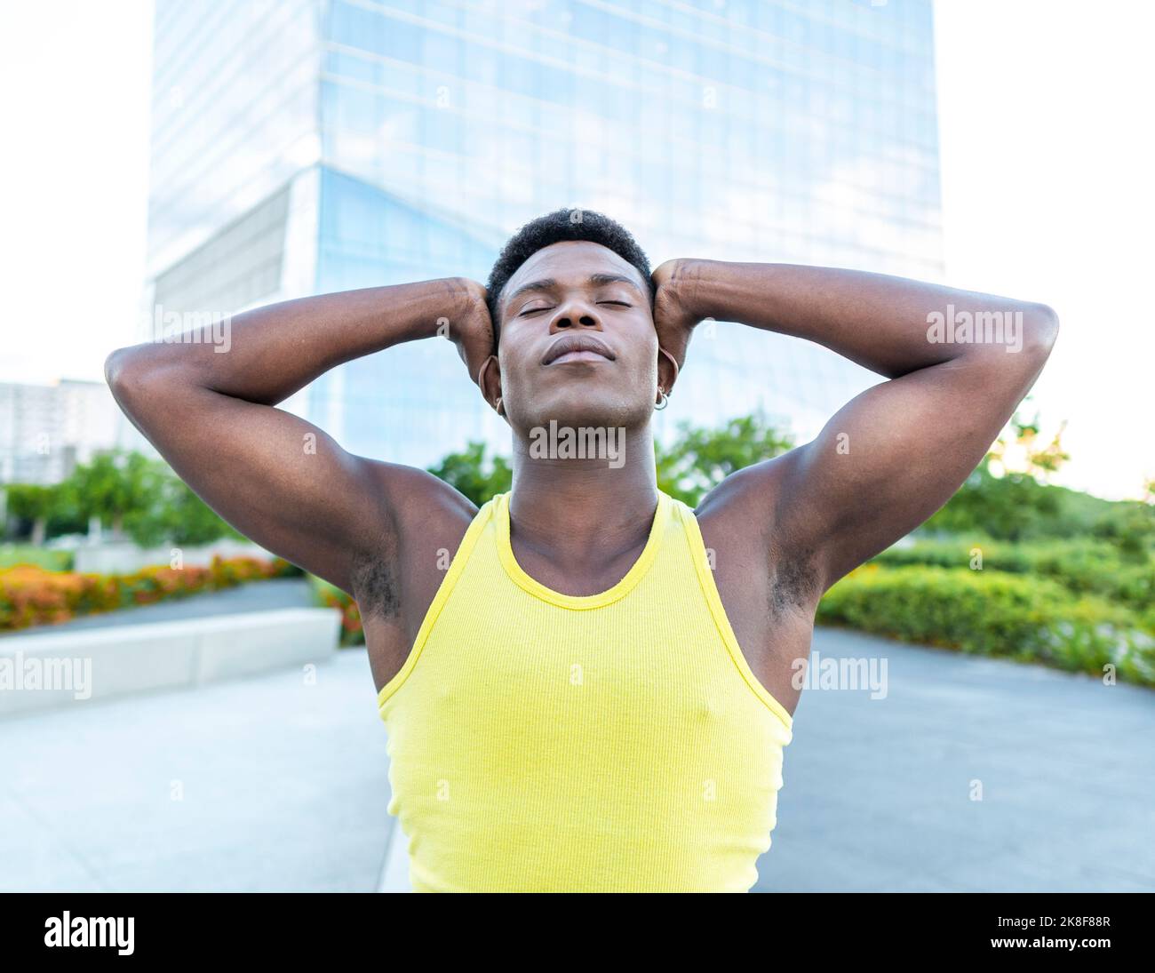Junger Mann mit gelber Weste und geschlossenen Augen auf dem Fußweg Stockfoto