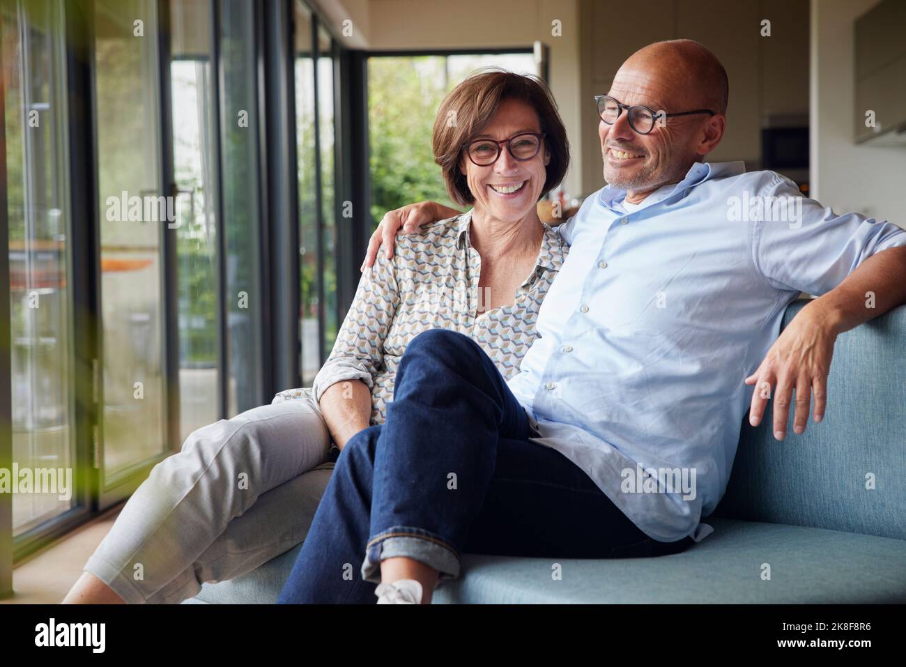 Fröhliches Seniorenpaar, das zu Hause auf dem Sofa sitzt Stockfoto