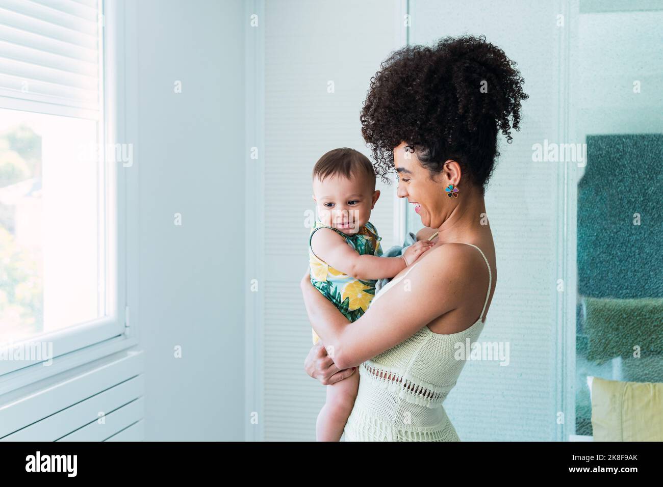 Glückliche Frau, die einen kleinen Jungen zu Hause trägt Stockfoto