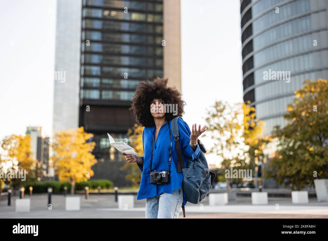 Verwirrte Afro-Frau mit Karte vor Gebäuden Stockfoto