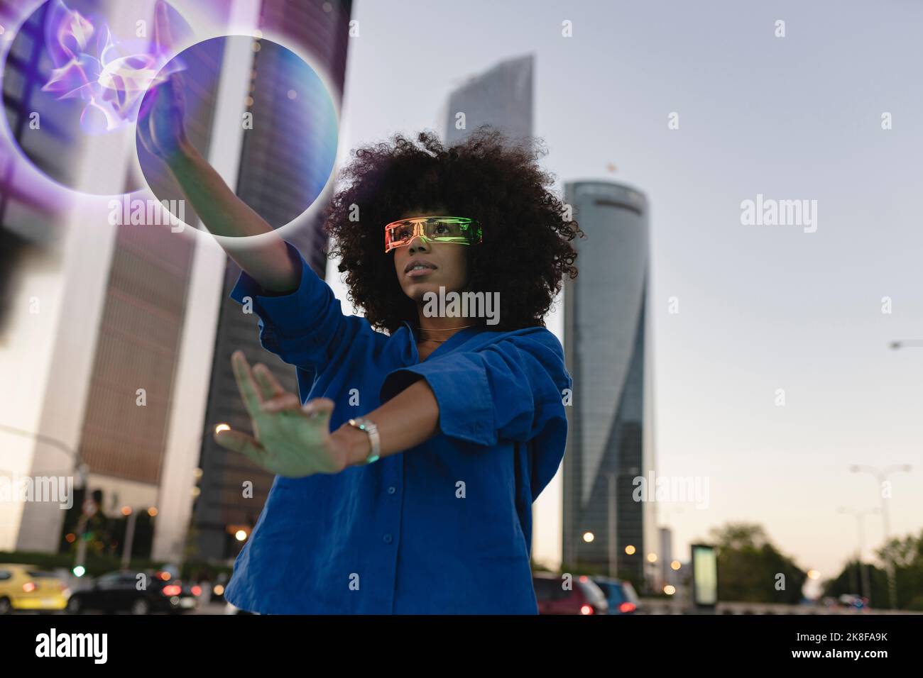 Afro-Frau trägt eine intelligente Brille und berührt den glühenden Ball Stockfoto