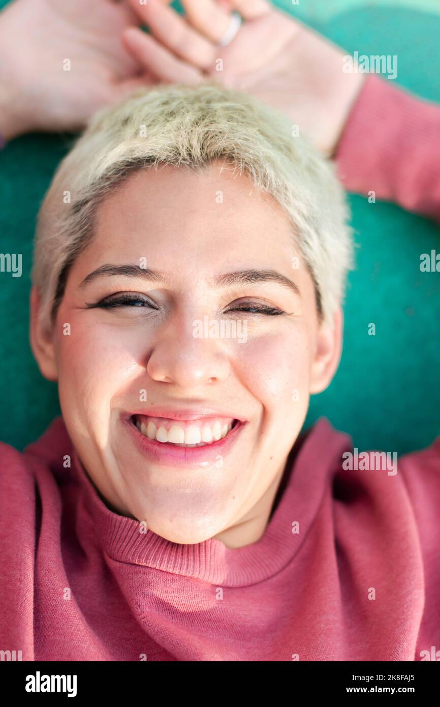 Fröhliche nicht-binäre Person liegt auf dem Sportplatz Stockfoto