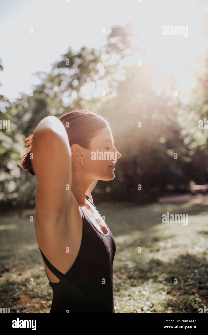 Yogalehrer mit geschlossenen Augen und Sonneneinstrahlung im Park Stockfoto