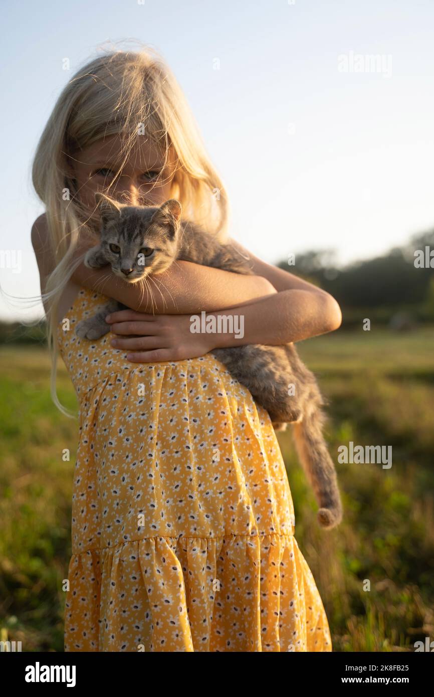Blonde Mädchen tragen Katze an sonnigen Tag Stockfoto