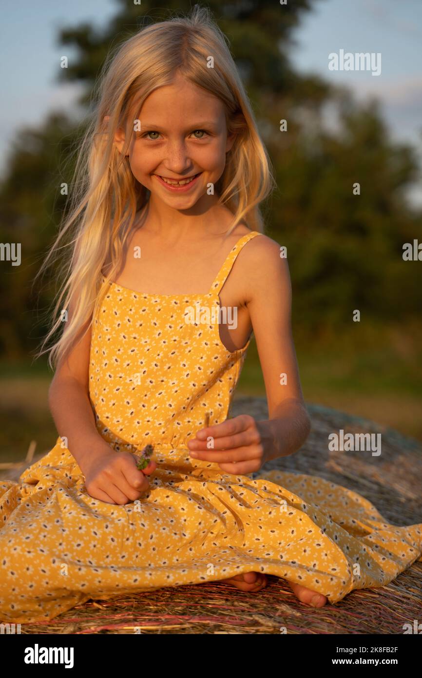 Lächelndes Mädchen mit blonden Haaren auf Heuhaufen Stockfoto