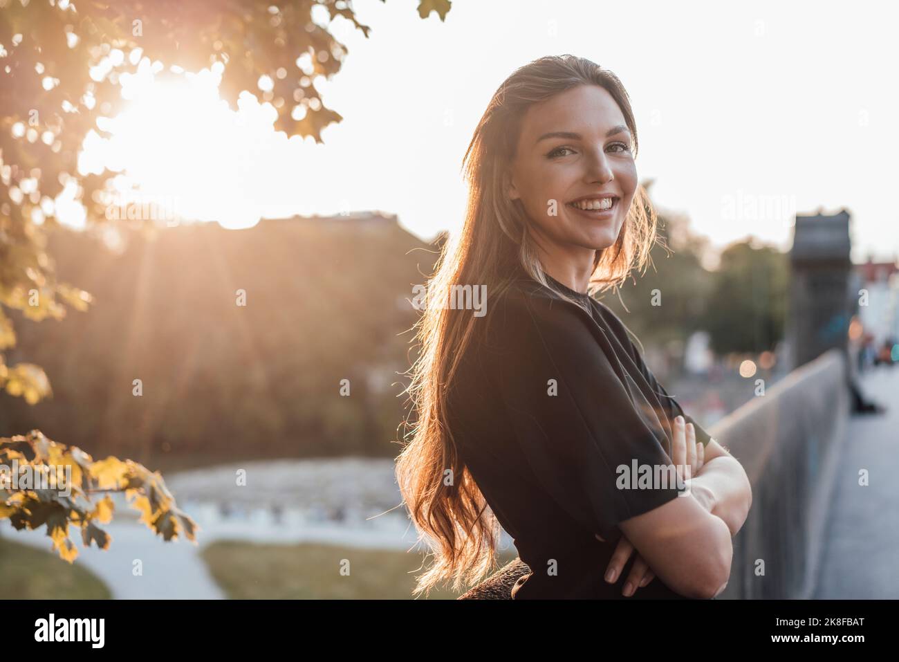 Glückliche junge Frau mit gekreuzten Armen, die an der Wand stehen Stockfoto