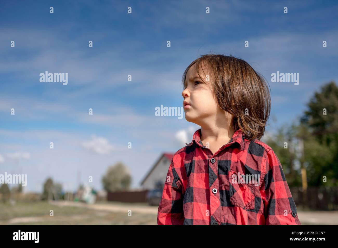 Nachdenklicher Junge mit karierten Hemden an sonnigen Tagen Stockfoto