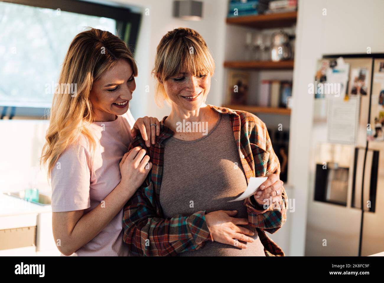 Lächelnde, werdende Frau, die der Schwester zu Hause Ultraschall zeigt Stockfoto