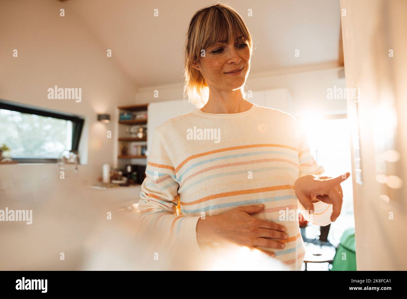 Schwanger Frau Betrieb Thermostat zu Hause Stockfoto