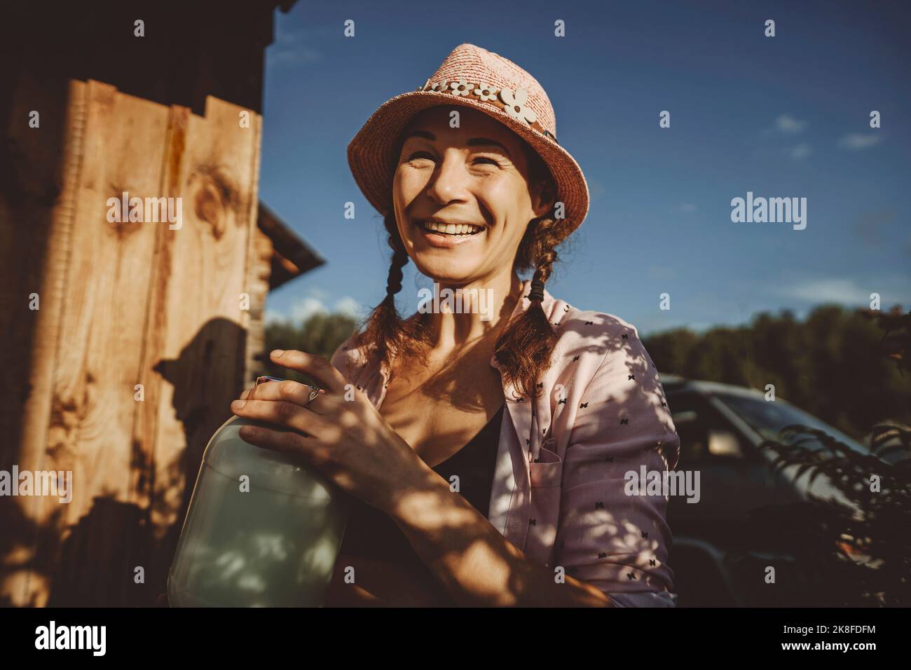 Glückliche Frau mit einem Glas Milch am sonnigen Tag Stockfoto