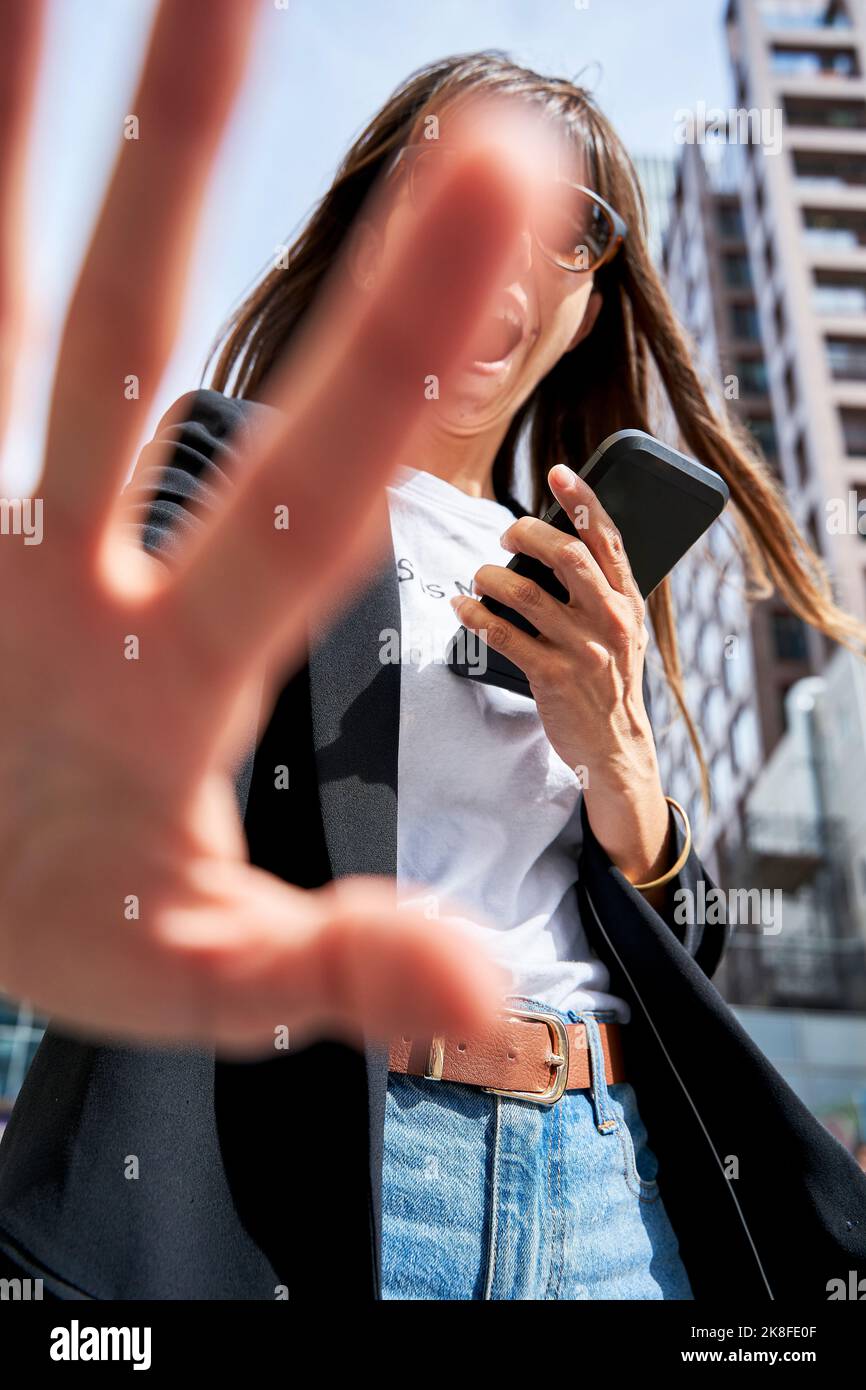 Frau mit Smartphone zeigt Stoppgeste mit der Hand Stockfoto