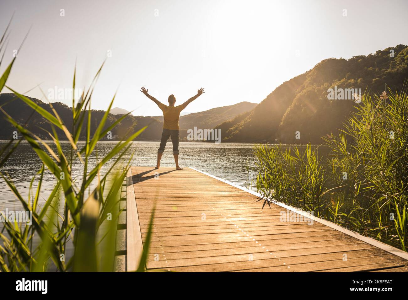 Reifer Mann, der im Urlaub mit erhobenen Armen auf dem Anlegesteg steht Stockfoto