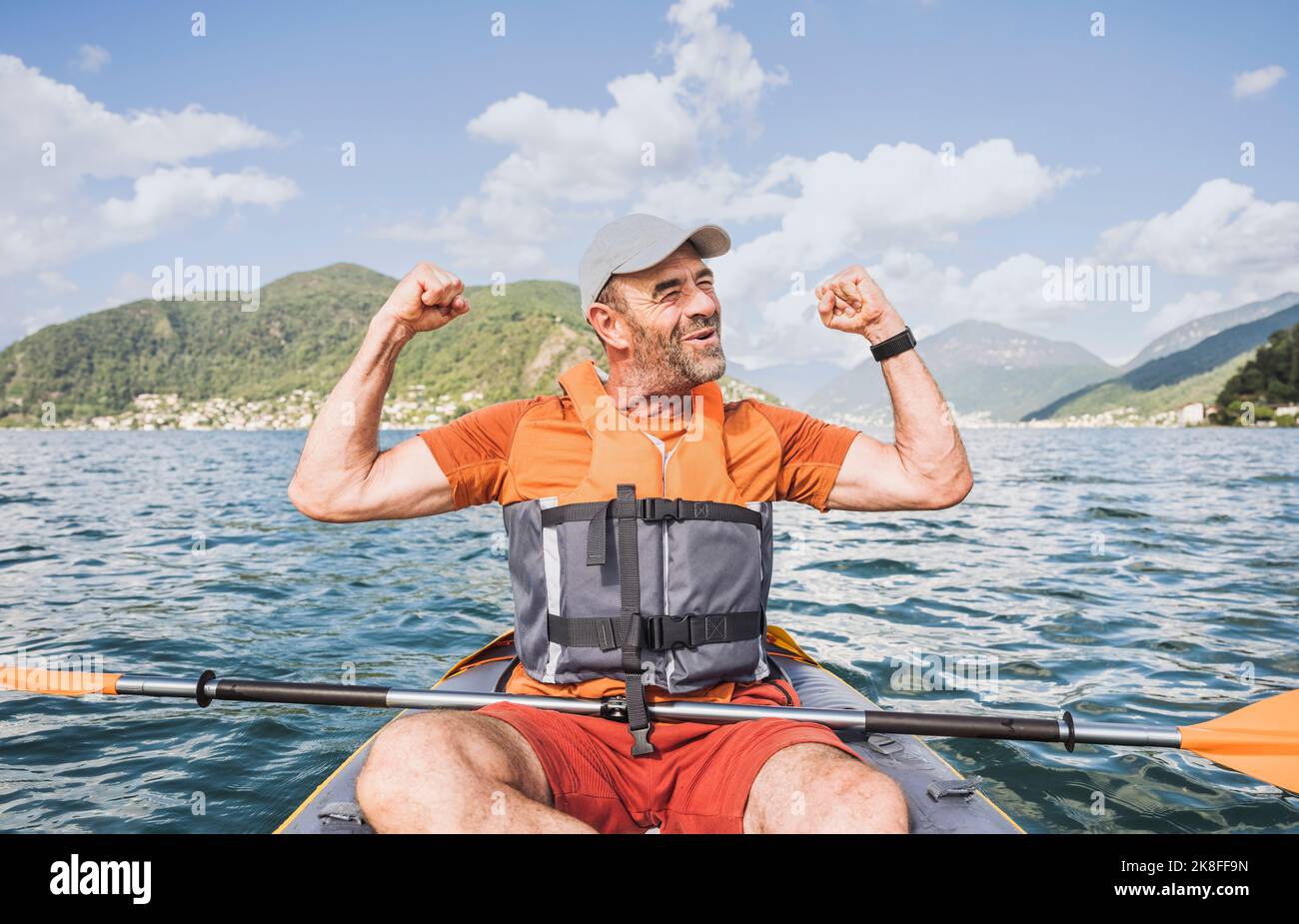 Aufgeregter Mann mit erhobenen Armen im Kajak sitzend Stockfoto
