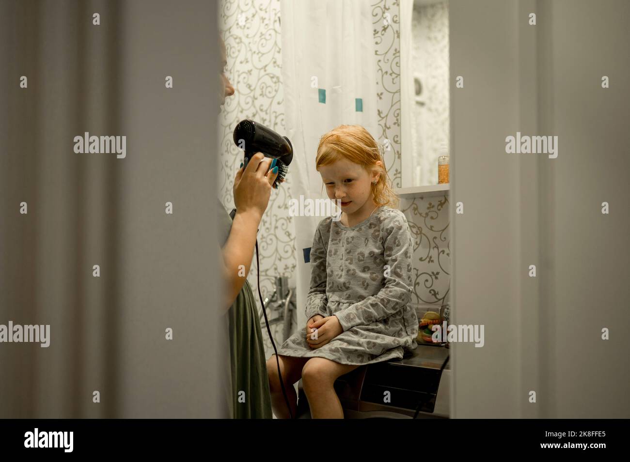 Mutter trocknet Haar der Tochter mit Fön zu Hause Stockfoto