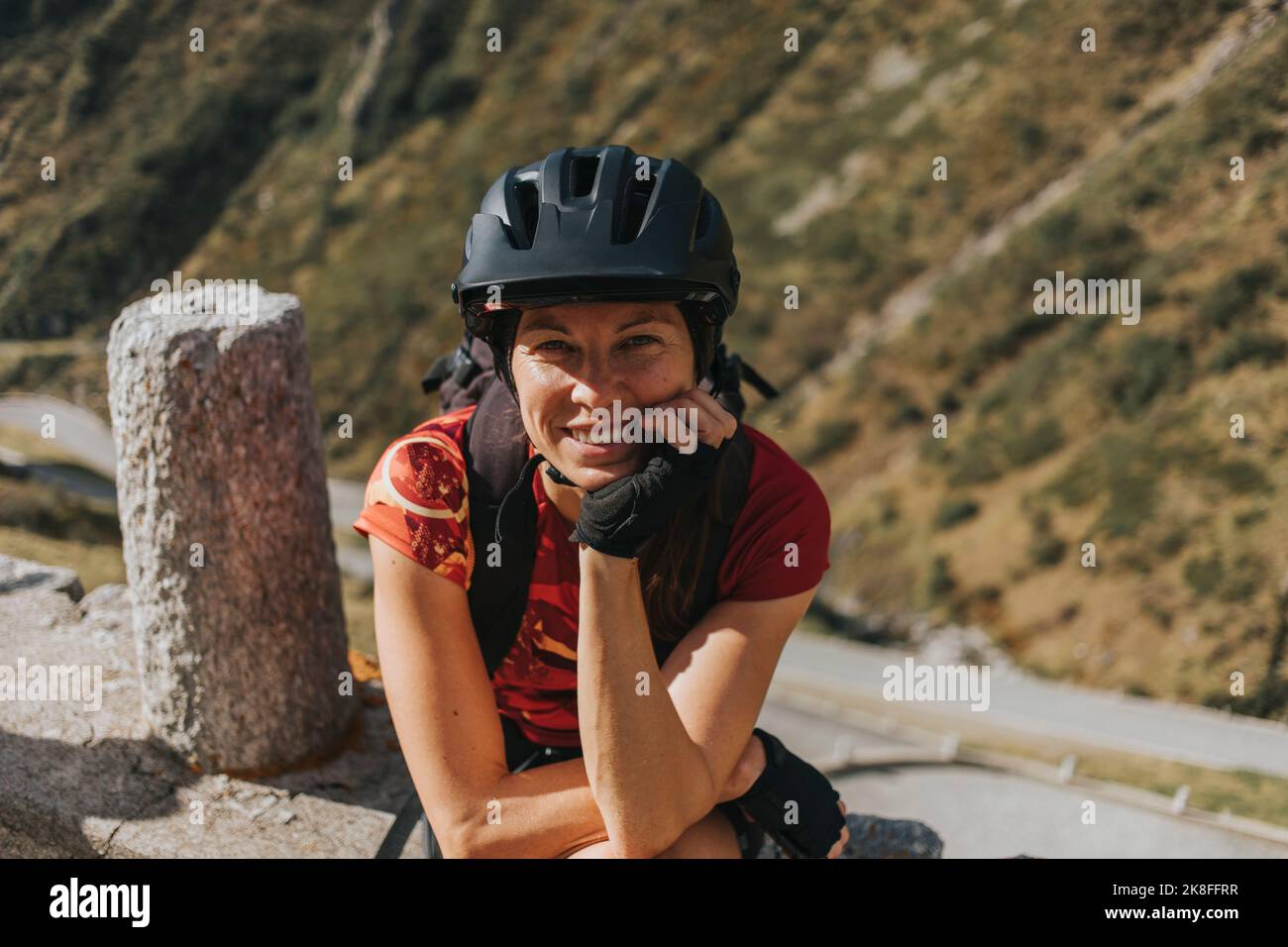 Glücklicher Radfahrer mit Helm, der sich am Ellbogen lehnt Stockfoto