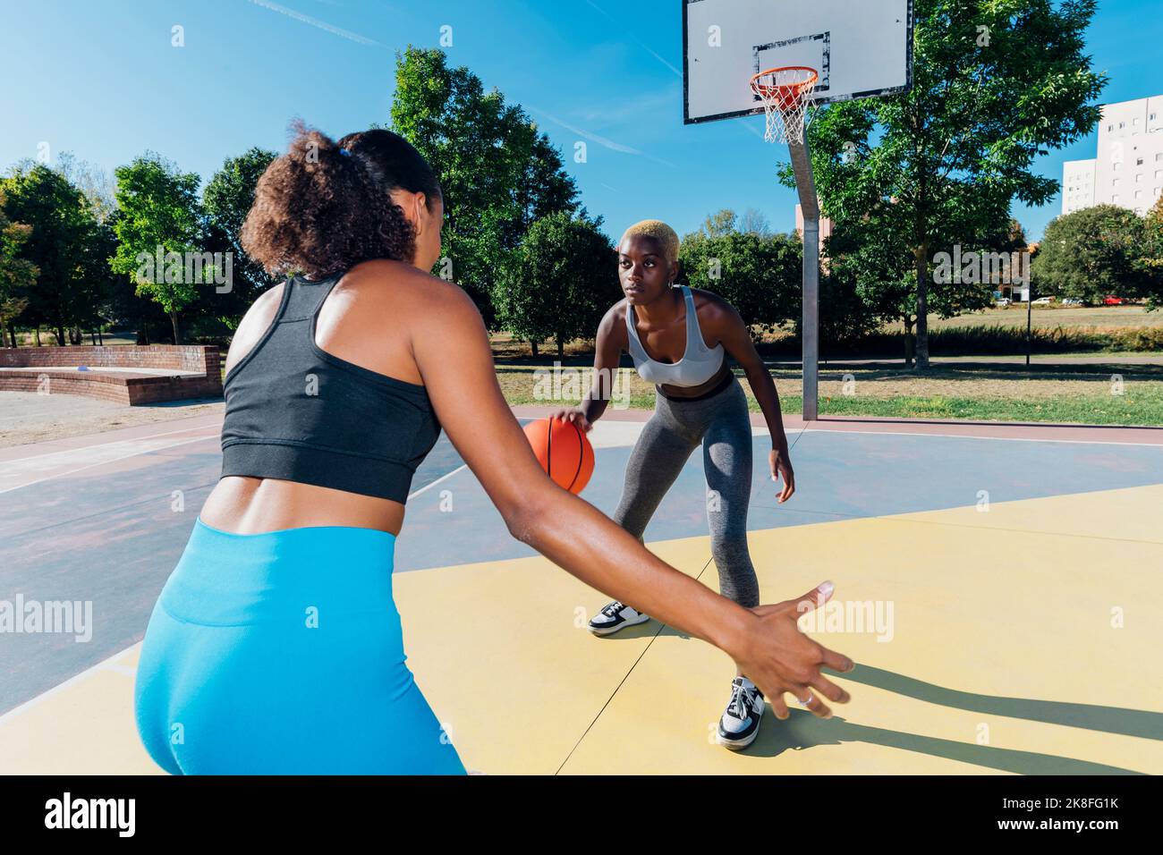 Junge Sportlerin Dribbling Basketball spielen mit Freund auf dem Sportplatz Stockfoto