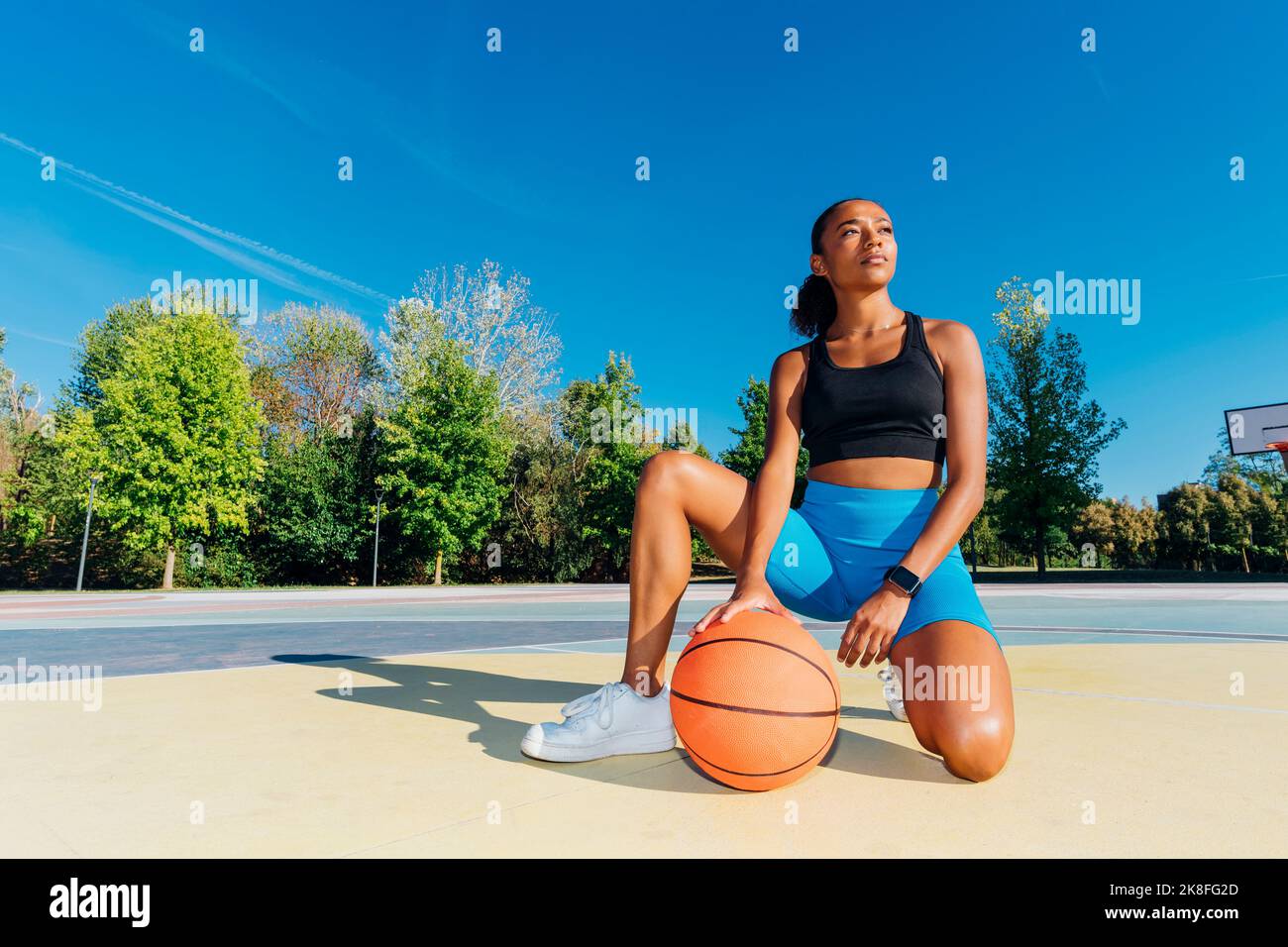 Beschauliche Sportlerin mit Basketball auf dem Sportplatz Stockfoto