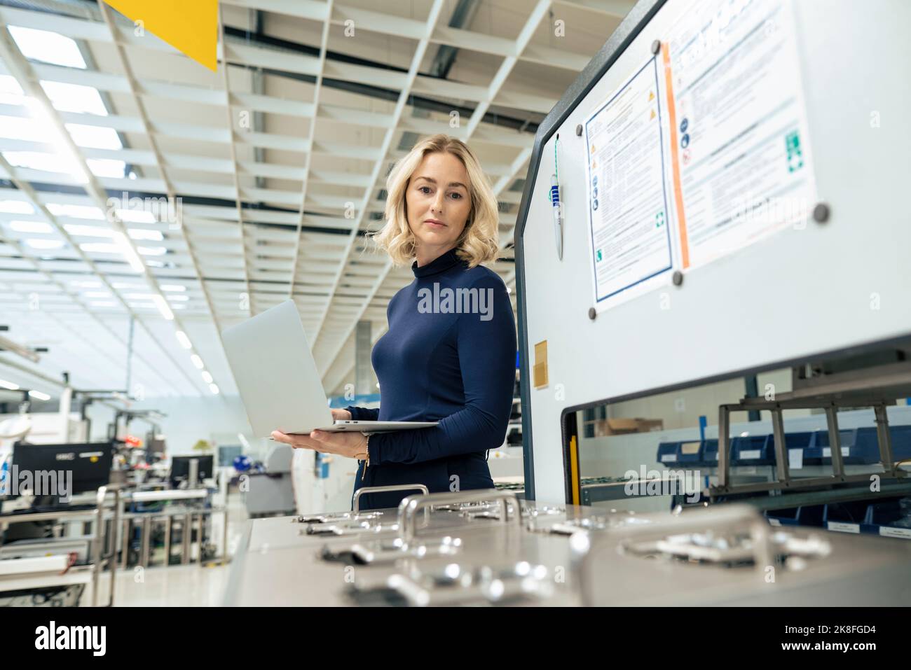 Lächelnde Geschäftsfrau mit Laptop im Lager Stockfoto