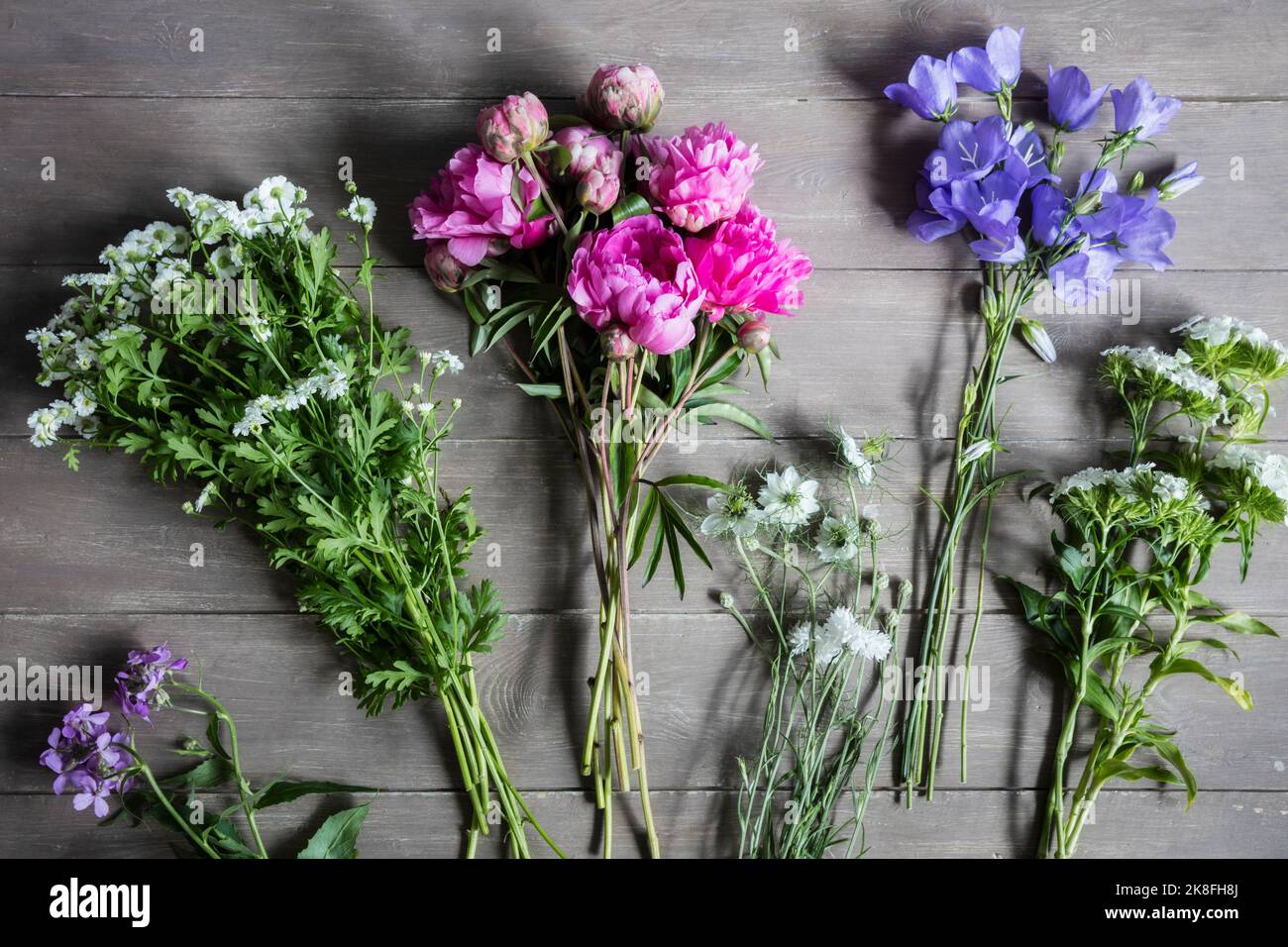 Blumensträuße mit saisonalen Blüten, die auf einer hölzernen Oberfläche liegen Stockfoto
