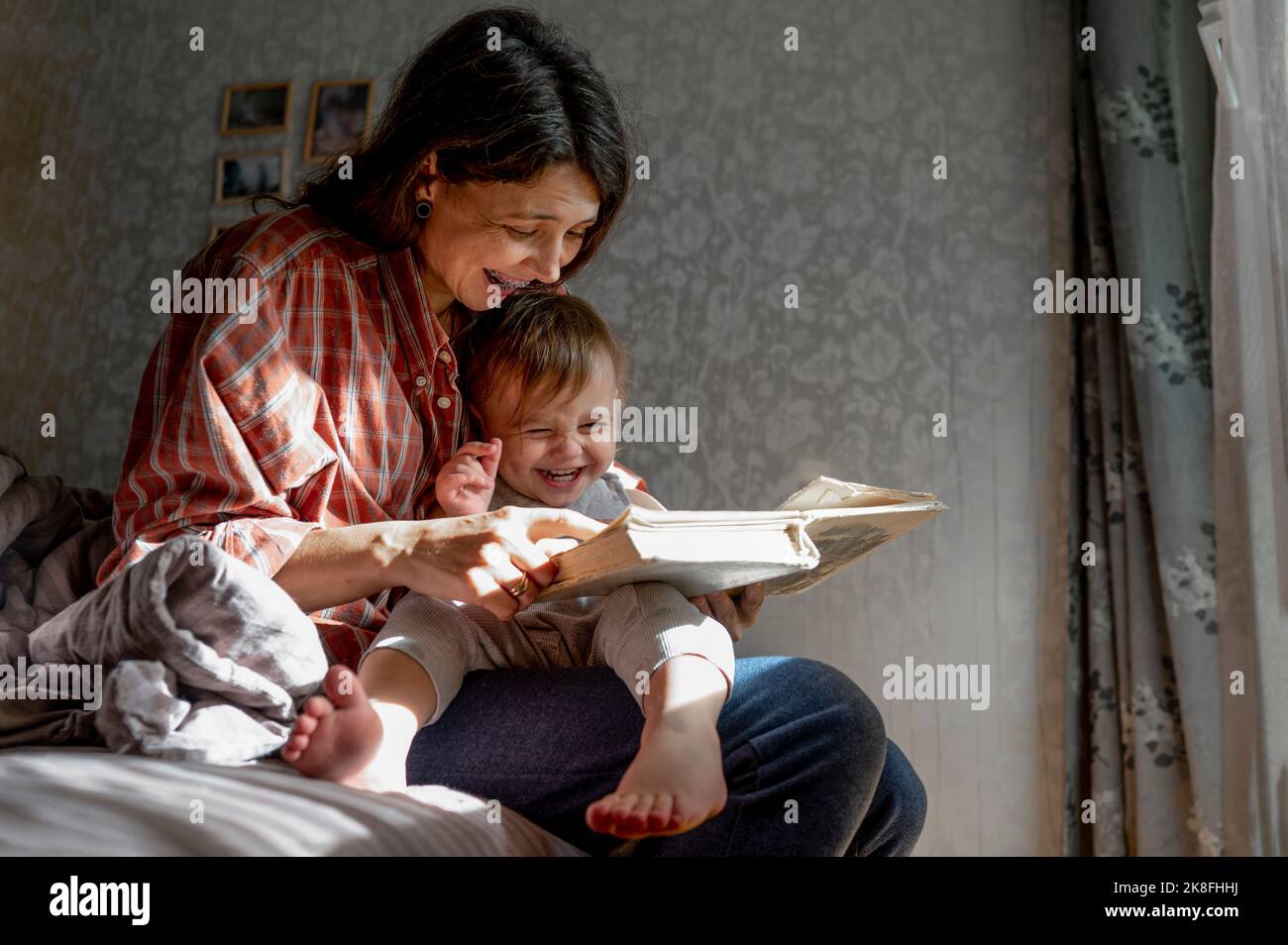 Glückliche Mutter mit Baby Buch zu Hause lesen Stockfoto