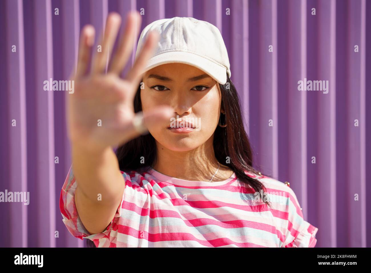 Junge Frau mit Mütze vor der Wand gestikuliert Stockfoto