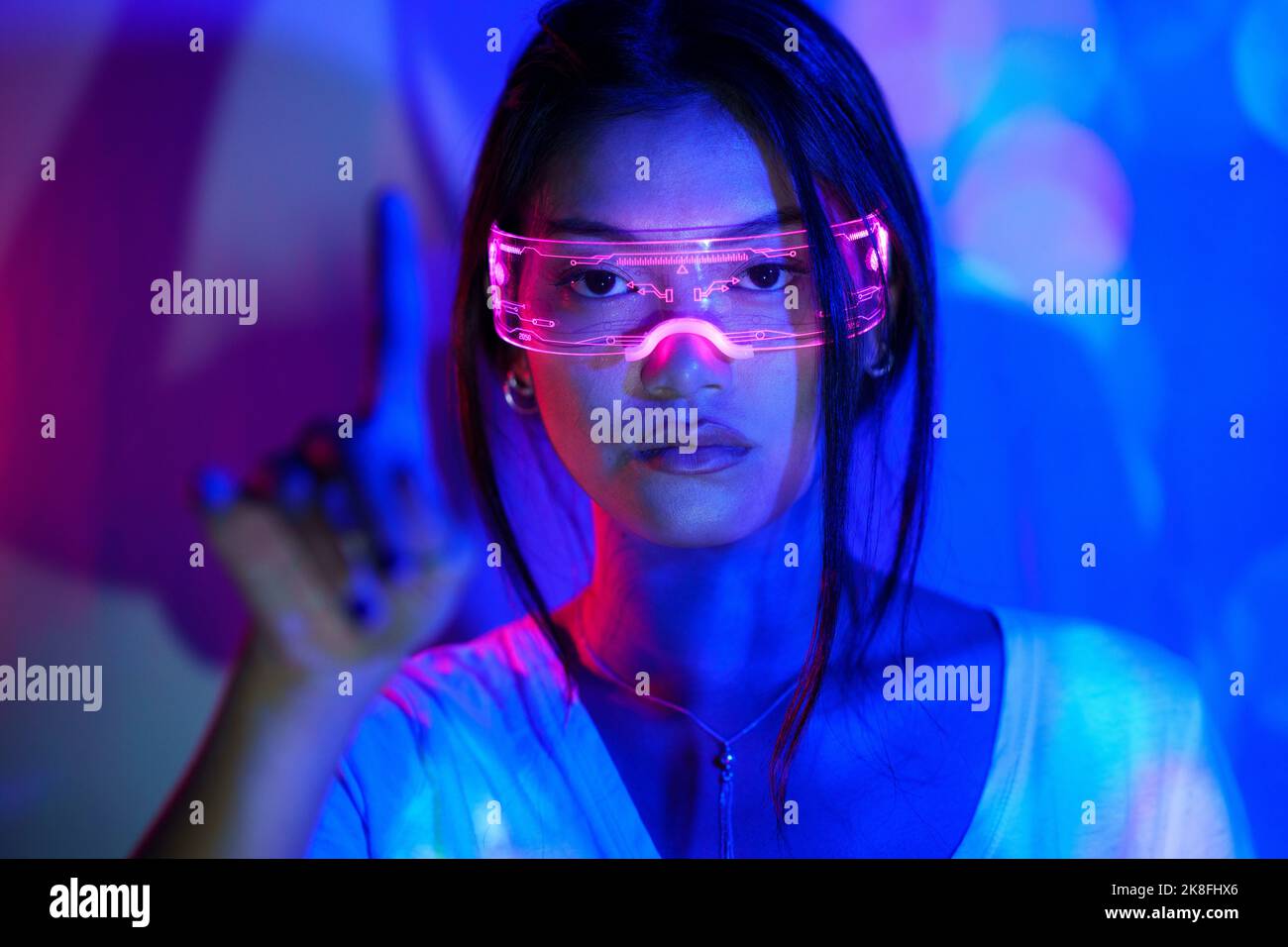 Junge Frau mit futuristischer Brille, die mit dem Finger gestikuliert Stockfoto