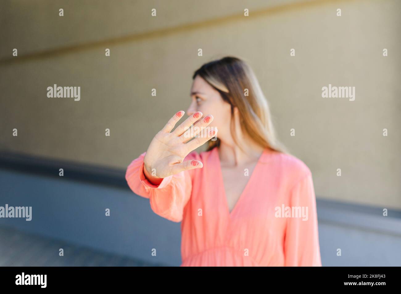 Frau gestikuliert Stoppschild mit Farbe auf den Fingern vor der Wand Stockfoto