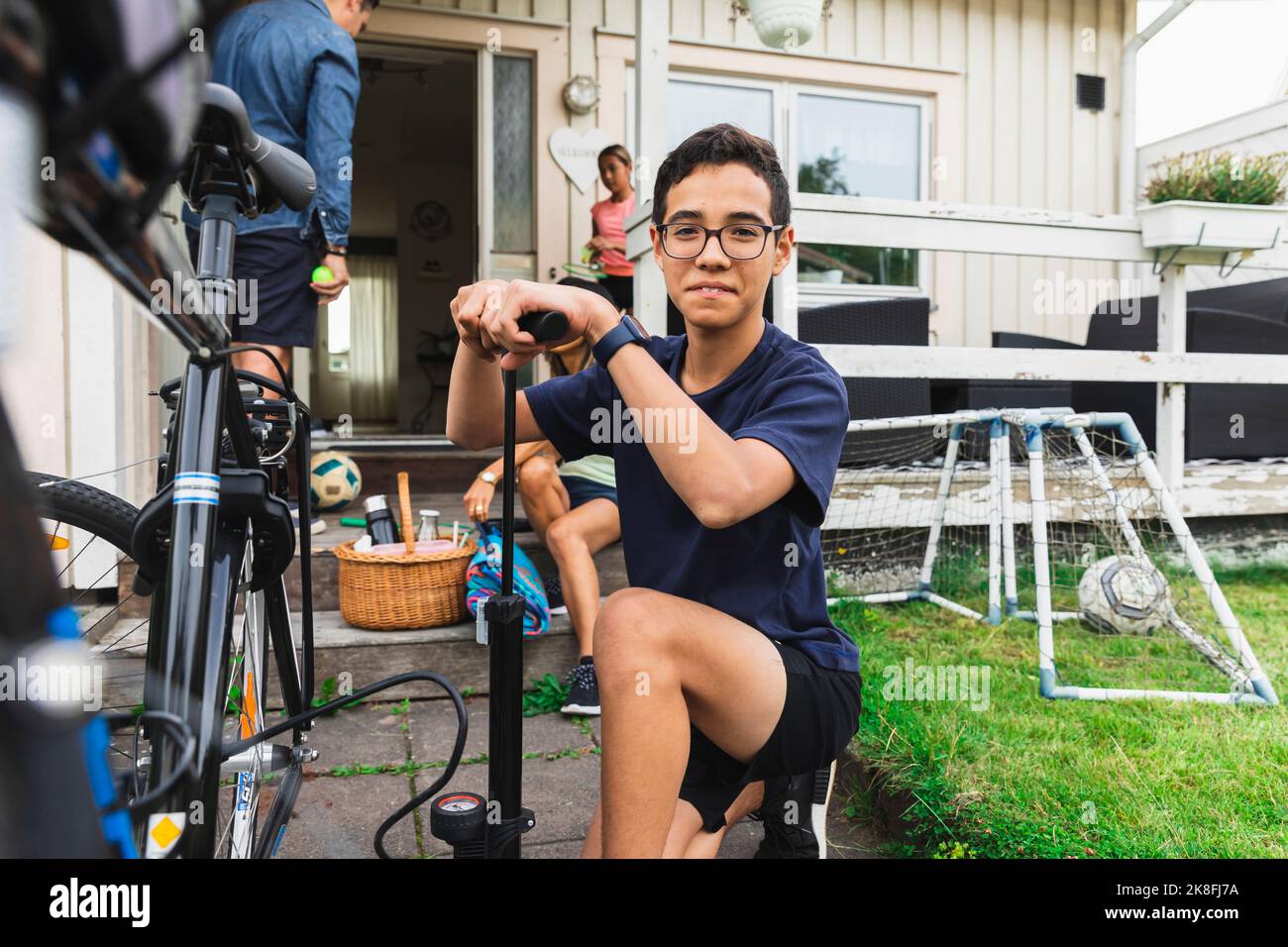 Lächelnder Junge, der Fahrradreifen vor dem Haus aufbläst Stockfoto