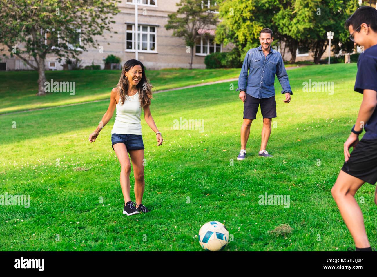 Glückliche Familie spielt Fußball auf Gras im Rasen Stockfoto