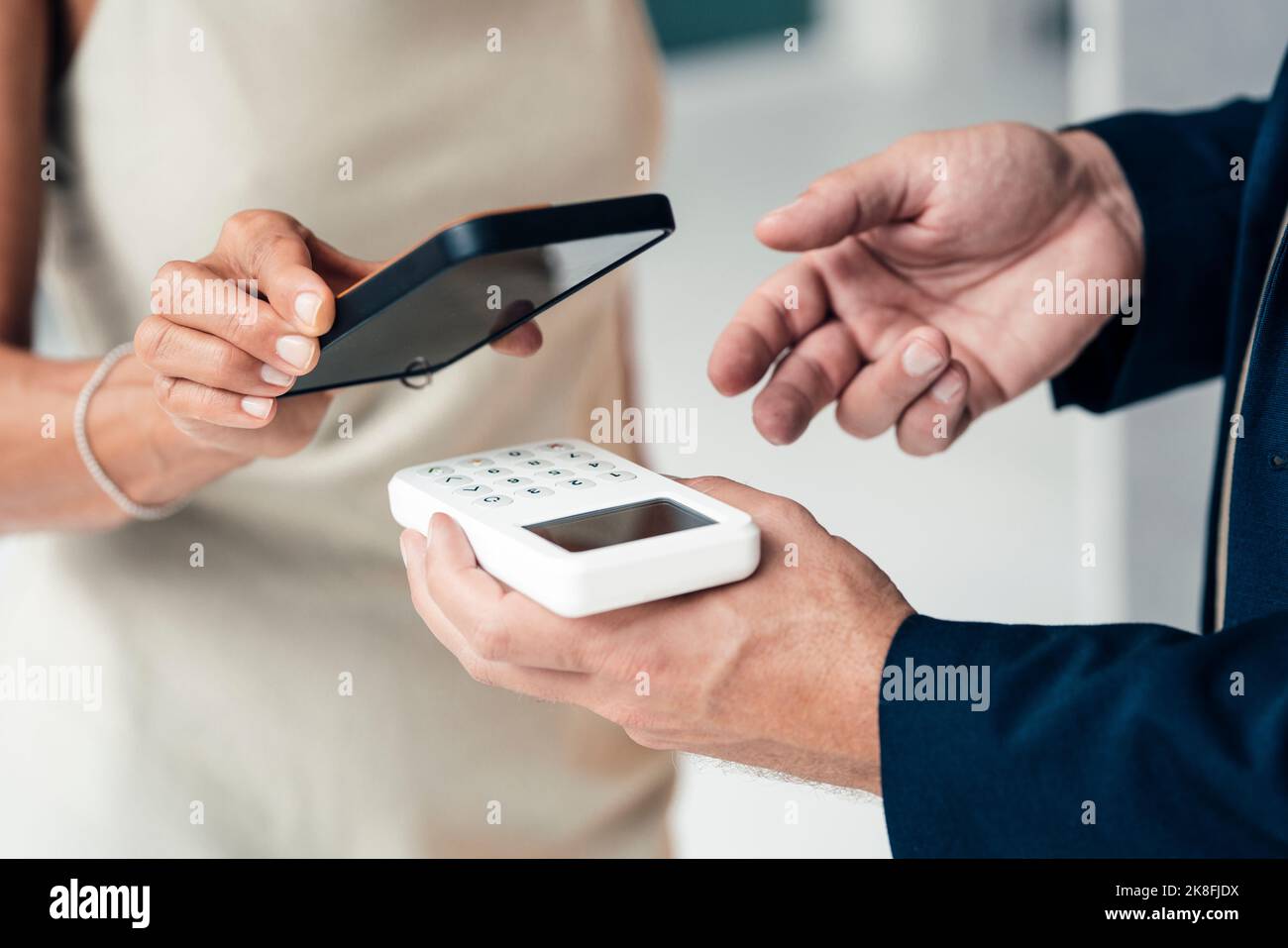 Hand eines Verkäufers mit Kreditkartenleser und einer zahlenden Frau Stockfoto