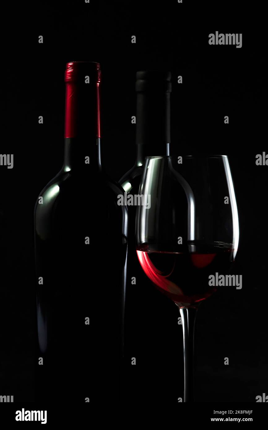 Dunkle Studioaufnahme von Flaschen und einem Glas Rotwein Stockfoto