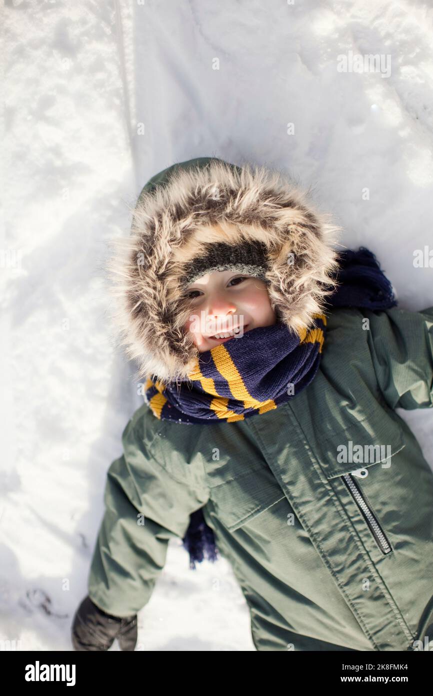 Lächelnder Junge liegt auf Schnee Stockfoto