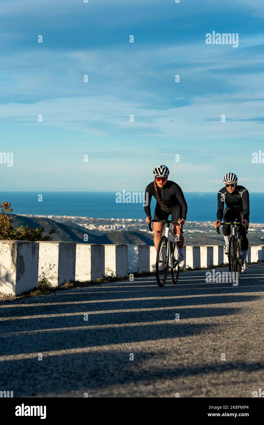 Sportlerin im Wettbewerb mit dem Sportler Radfahren auf dem Bergpass der Costa Blanca in Alicante, Spanien Stockfoto