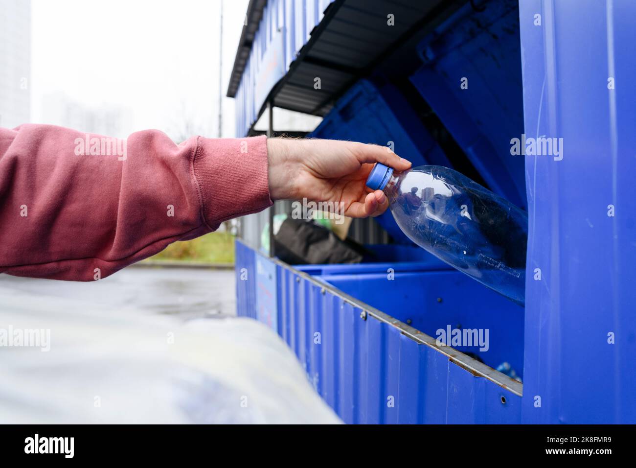 Hand eines Mannes, der Plastikflasche in den Müll wirft Stockfoto