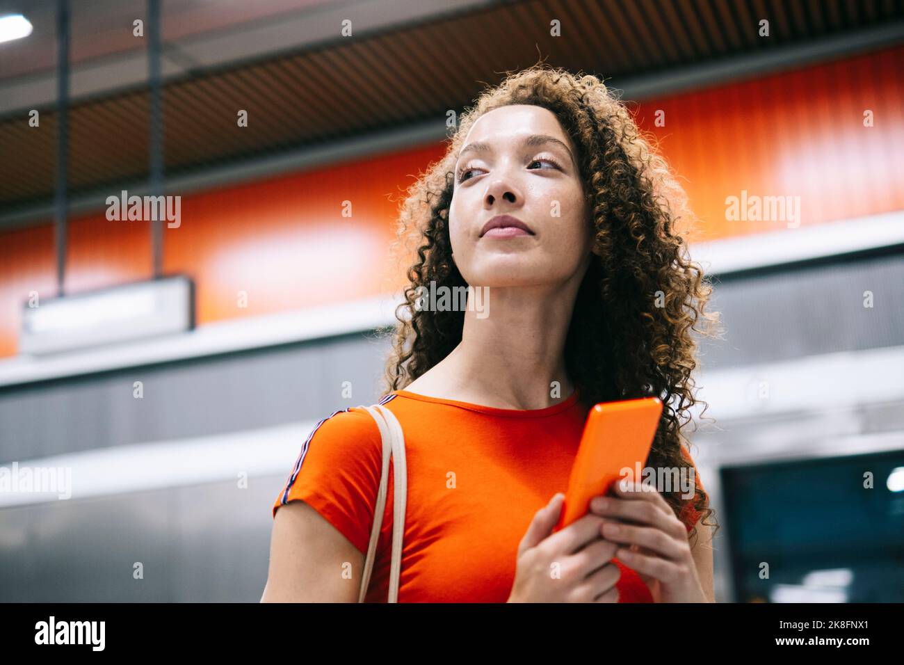 Junge Frau mit Mobiltelefon steht an der U-Bahn-Station Stockfoto
