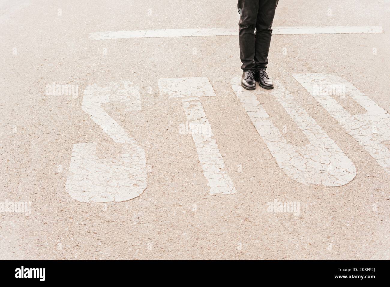 Die Beine des Mannes auf DEM STOPPSCHILD an der Straße Stockfoto