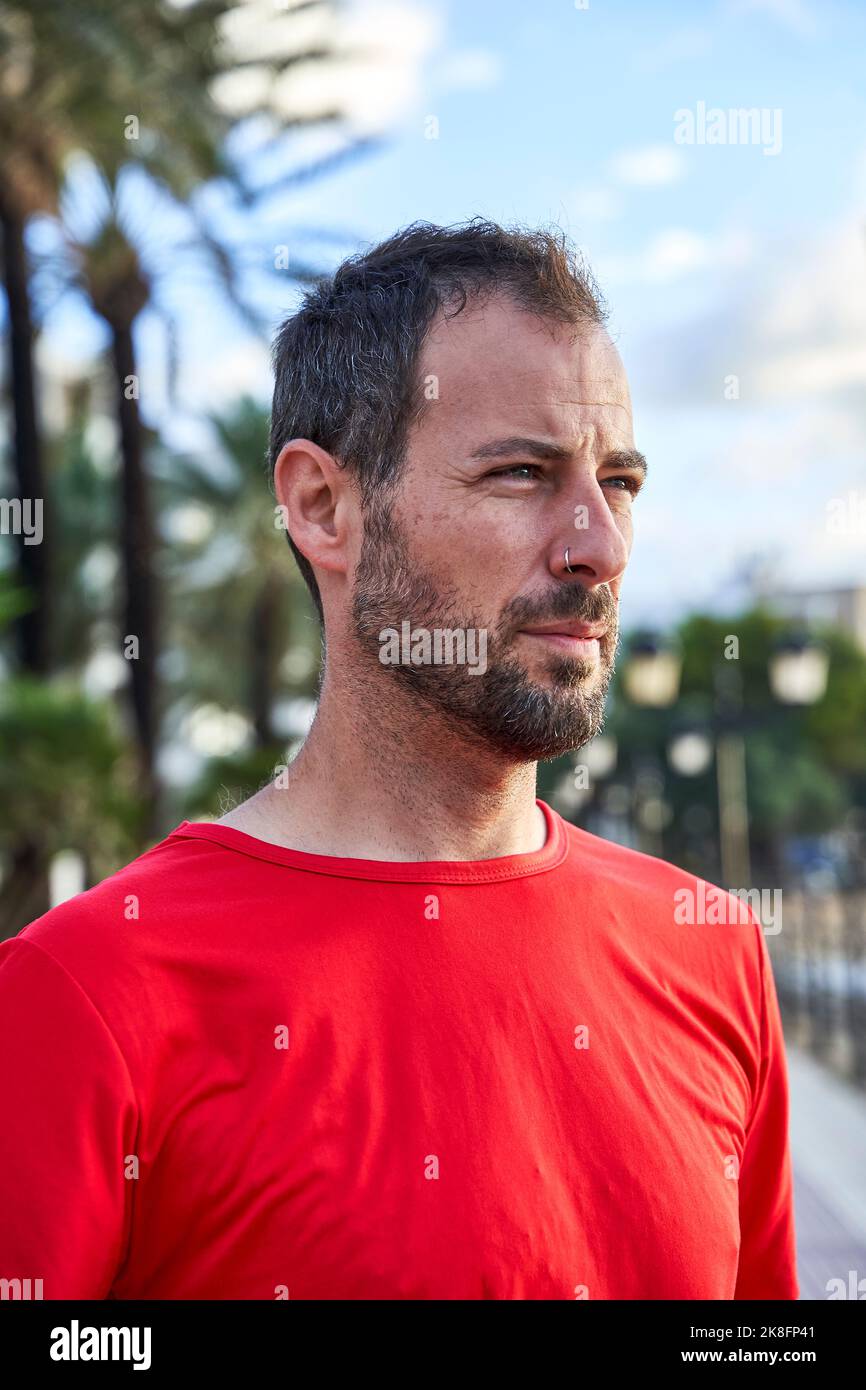 Mann trägt rotes T-Shirt auf dem Fußweg Stockfoto