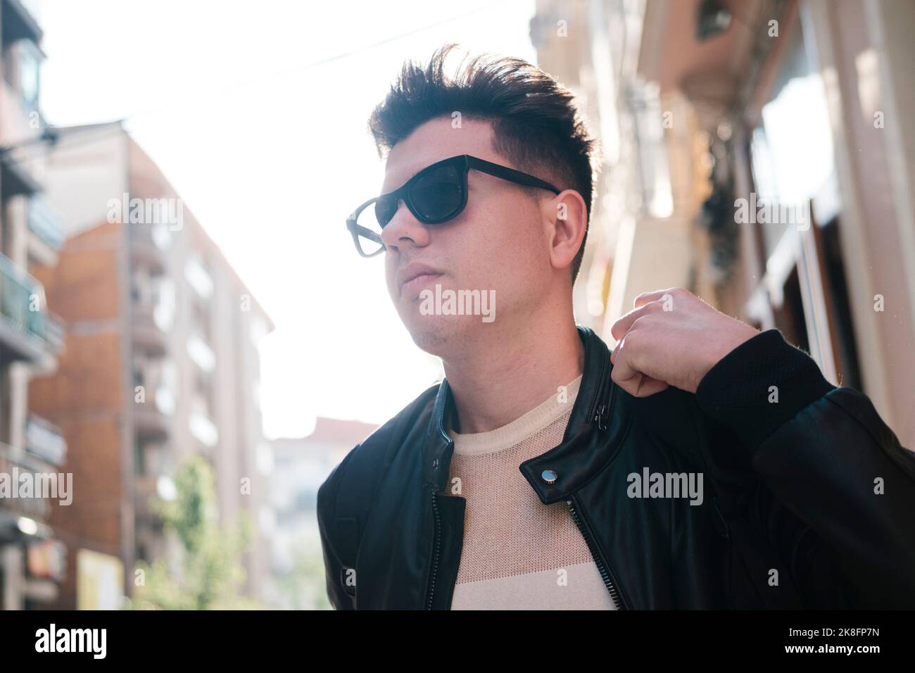 Junger Mann mit Sonnenbrille vor dem Gebäude Stockfoto