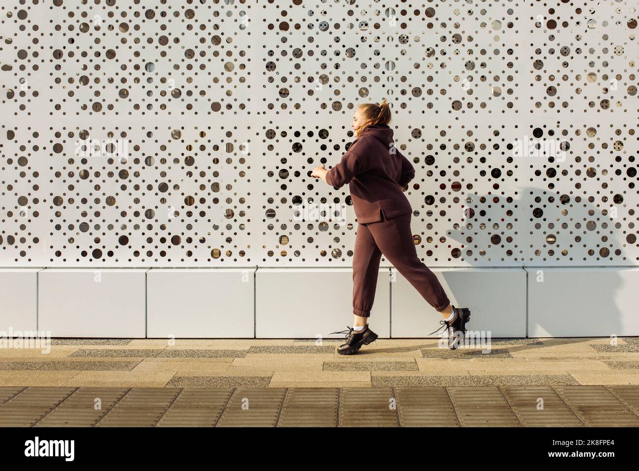 Plus size Frau joggt an der Wand Stockfoto