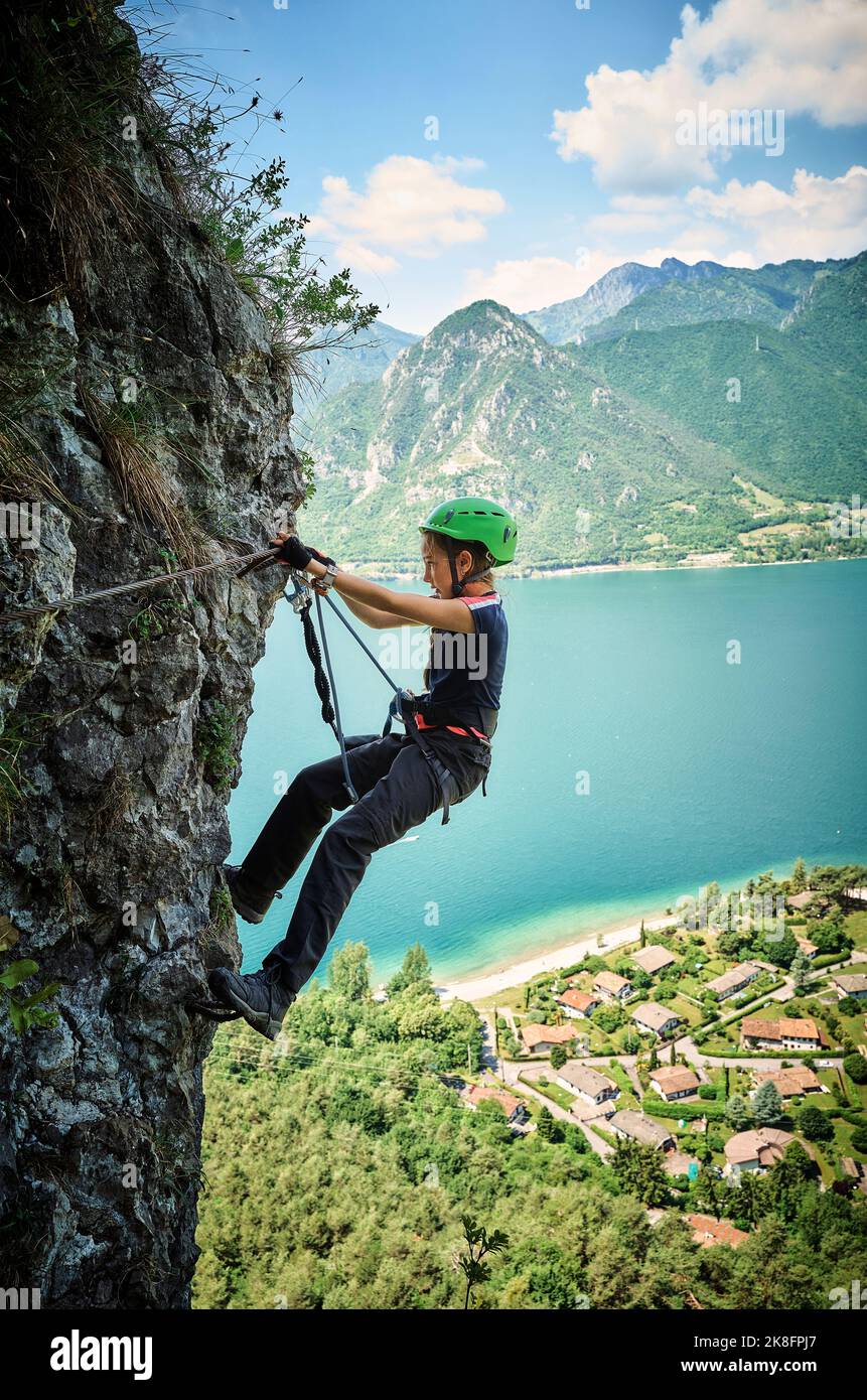 Mädchen klettert auf den Berg mit dem Idrosee im Hintergrund Stockfoto