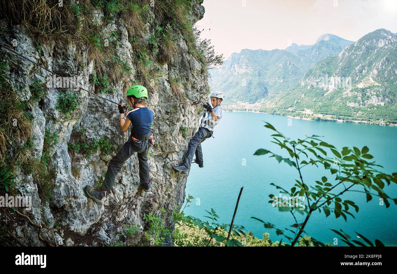 Mädchen mit Bruder beim Bergsteigen mit dem Idrosee im Hintergrund Stockfoto
