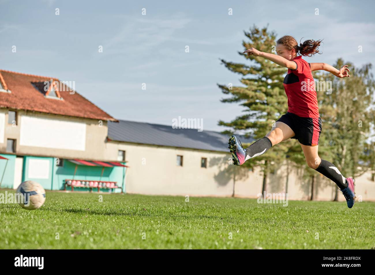 Mädchen springen auf dem Fußballplatz an sonnigen Tag Stockfoto