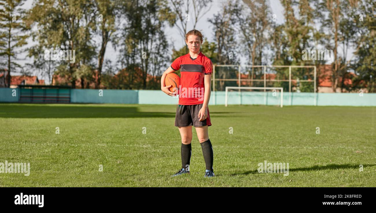 Mädchen mit Rugby-Ball auf dem Feld stehen Stockfoto