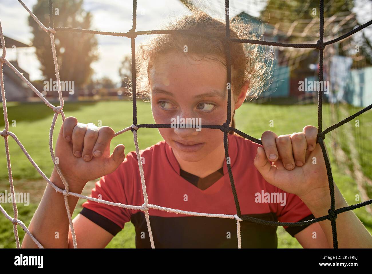 Mädchen durch das Netz auf dem Sportplatz an sonnigen Tag gesehen Stockfoto