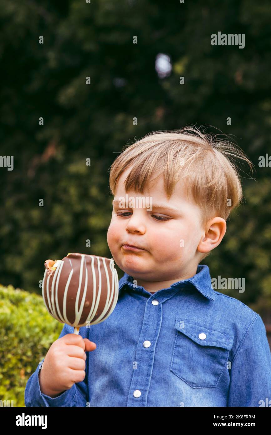 Niedlicher Junge mit Tafellapfel im Park Stockfoto