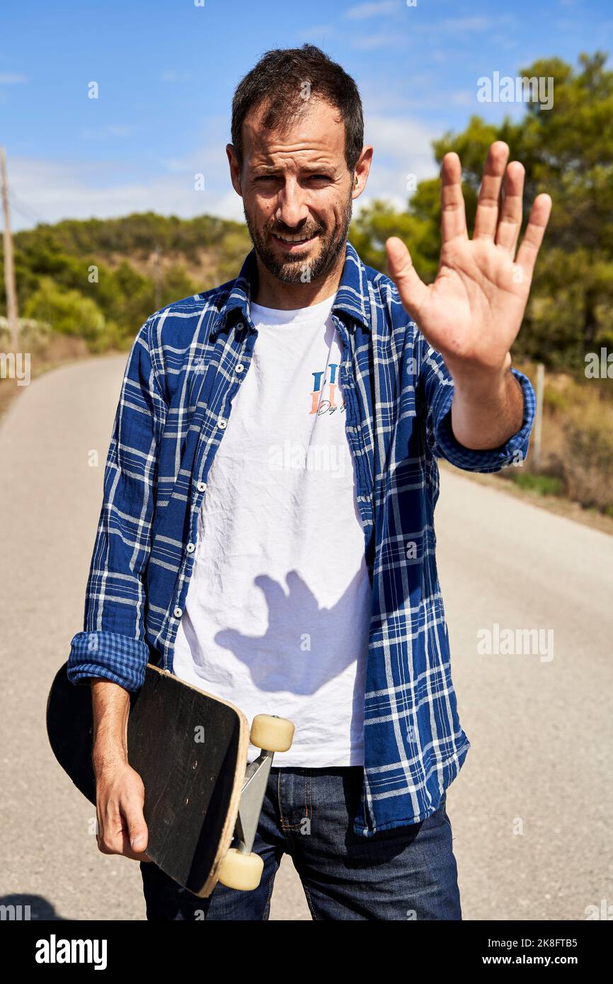 Mann mit Skateboard gestikulierenden Stoppschild an sonnigen Tag Stockfoto