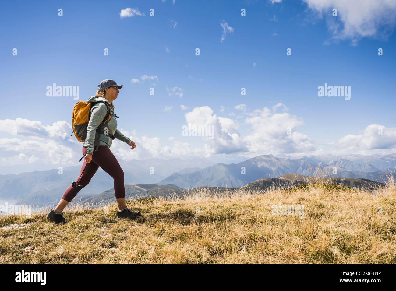 Reife Frau, die unter bewölktem Himmel auf Gras läuft Stockfoto